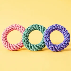 Multicolor cotton rope ring dog toy in orange, teal, and purple on a beige background