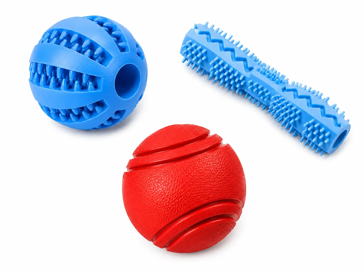 Assortment of rubber dog toys — a dental groove ball, a textured chew stick, and a solid bounce ball