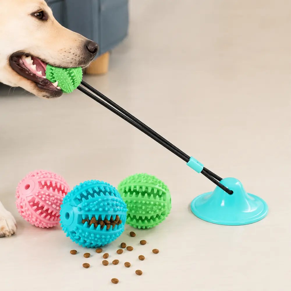 Suction cup dog toy in pink, teal, and green with a dog chewing the treat-filled ball