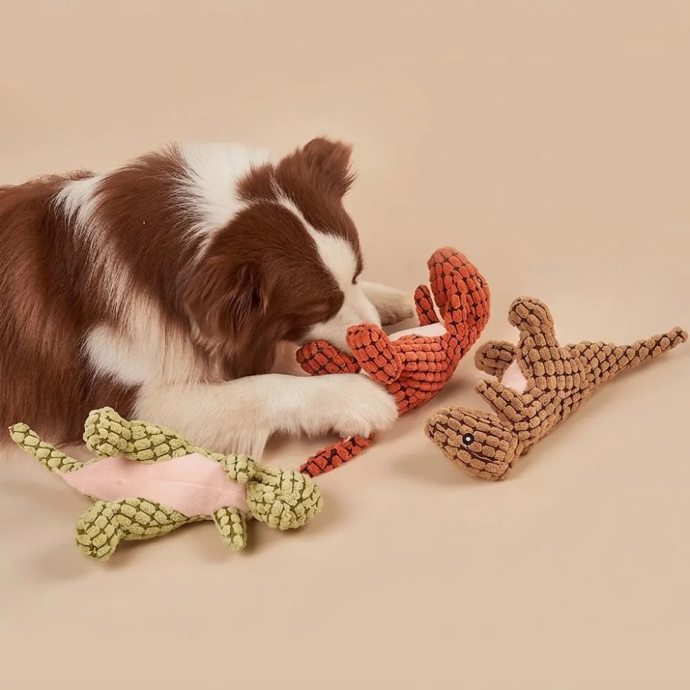 Border collie playing with green, orange, and brown dinosaur plush toys